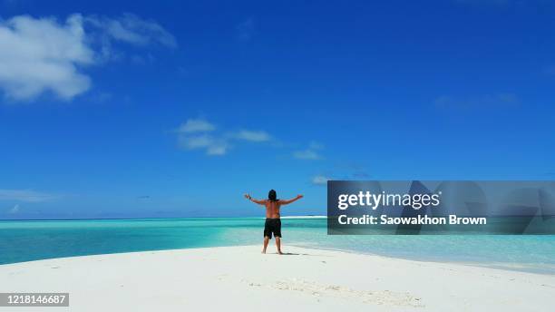 happy single man raise his hand into sky standing on man standing on deserted island of the maldives - einsame insel stock-fotos und bilder