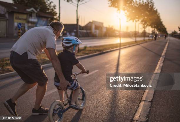 grandfather teaching grandson biking - pushing bike stock pictures, royalty-free photos & images