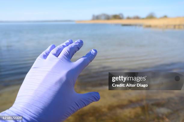 wish concept.light at the end of the tunnel. extended human hand with protection globes in a beach´s lake. germany. - beckoning stock pictures, royalty-free photos & images