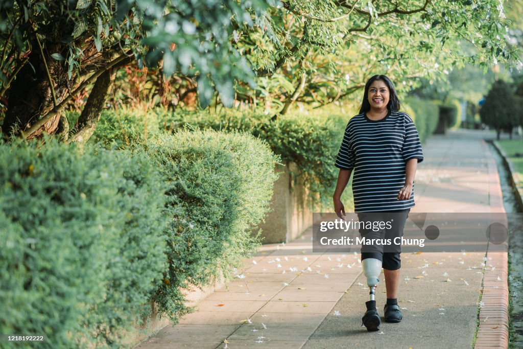 Aziatische Indiër die met prothetisch been glimlacht dat vrouw jogging en in het openbare park op zonnige dag uitoefent