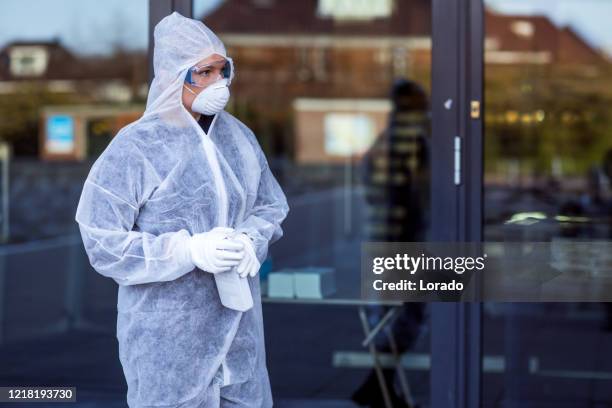 una trabajadora esencial que lleva una máscara facial durante el brote de virus - mono blanco traje protector fotografías e imágenes de stock