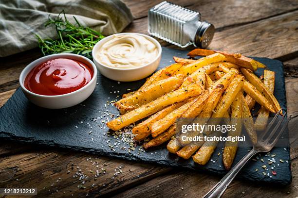 homemade french fries with ketchup and mayonnaise on rustic wooden table - french fries stock pictures, royalty-free photos & images