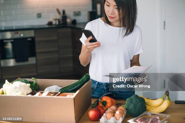 young woman checking food delivery with smartphone - shopping list stock pictures, royalty-free photos & images