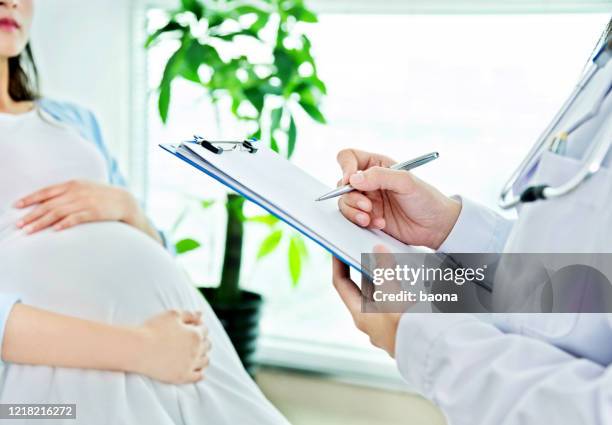 doctor writing notes for pregnant woman - office cross section stock pictures, royalty-free photos & images