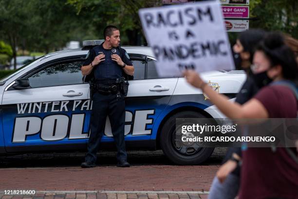Winter Park police officer watches protesters march during a rally in response to the recent death of George Floyd while in police custody in...