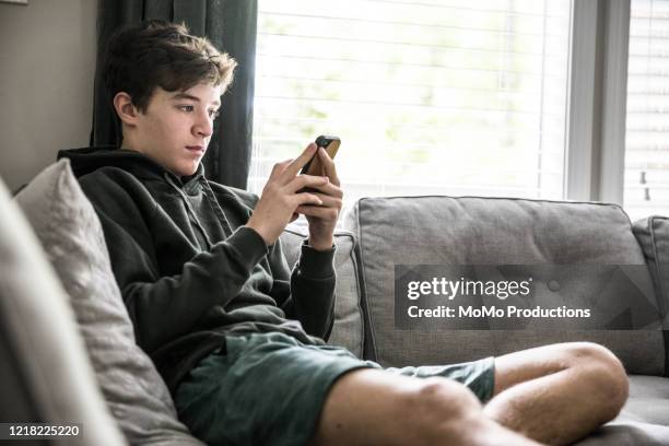 teenage boy using smartphone at home - teen boy shorts stock pictures, royalty-free photos & images