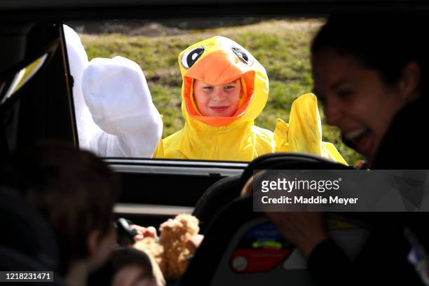 Boston Phillips dressed as a chick, waves to children during a drive-through Easter photo session at StoryHeights Church on April 11, 2020 in Newton,...