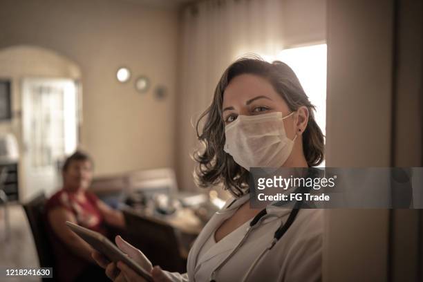portrait of health visitor and a senior woman during home visit - healthcare and medicine real stock pictures, royalty-free photos & images