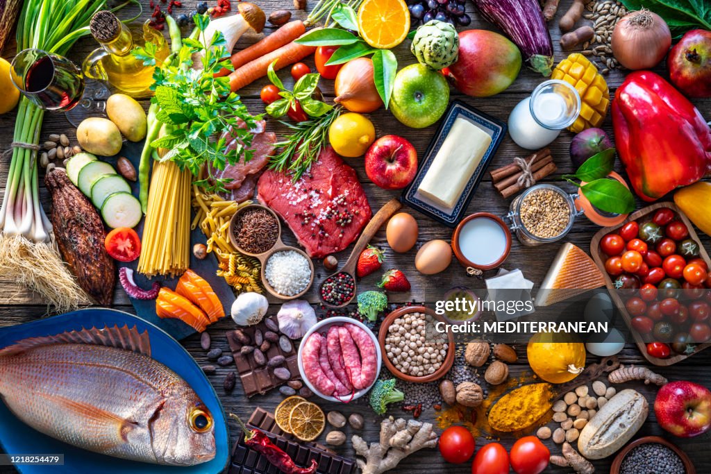 Varied food carbohydrates protein vegetables fruits dairy legumes on wood