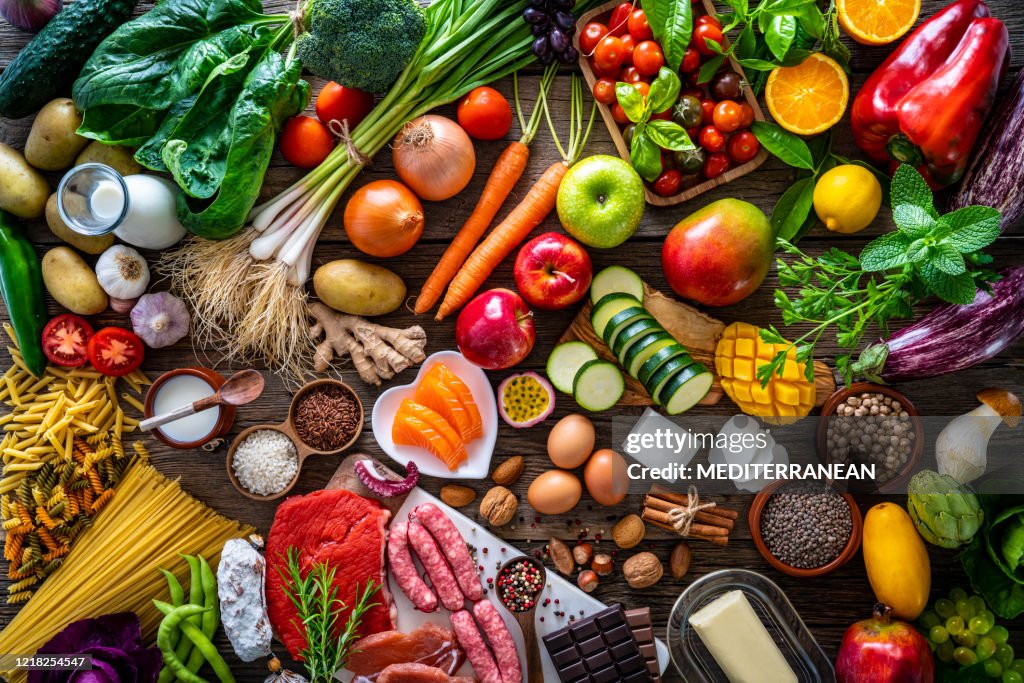Varied food carbohydrates protein vegetables fruits dairy legumes on wood