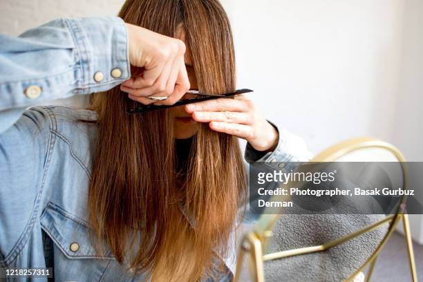 a woman cutting her own hair - human hair stockfoto's en -beelden