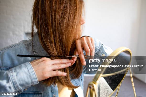 a woman cutting her own hair - haardracht stockfoto's en -beelden