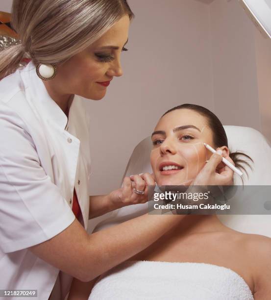 dermatologist woman surgeon drawing lines on woman's face for plastic surgery - beauty treatment stock pictures, royalty-free photos & images