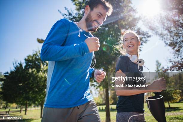 cheerful couple having fun running together - men jogging stock pictures, royalty-free photos & images