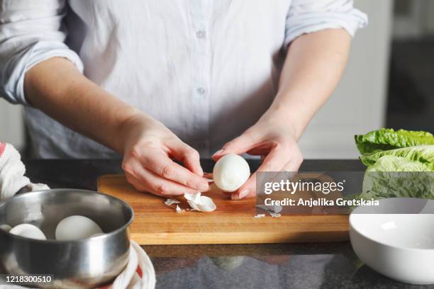 female hands is shelling chicken eggs. the woman prepares salad - geschält stock-fotos und bilder
