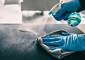 Surface sanitizing against COVID-19 outbreak. Home cleaning spraying antibacterial spray bottle disinfecting against coronavirus wearing nitrile gloves. Sanitize hospital surfaces prevention