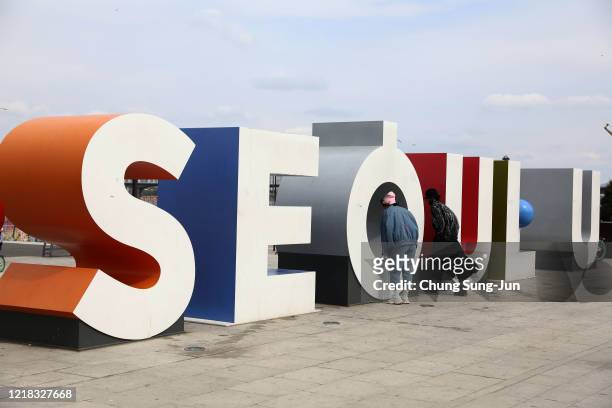 People pose for photos on an installation spelling 'Seoul', during a Easter holiday at Yeouido park as South Koreans take measures to protect...