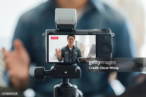 young man vlogging through video camera at home - influencer marketing stockfoto's en -beelden