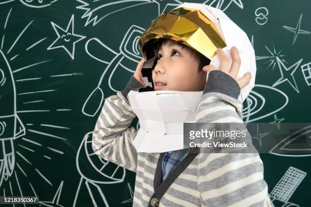 wearing a helmet of astronauts little boy standing in front of the blackboard - tafel kind rakete stock-fotos und bilder