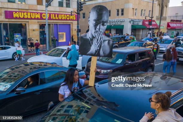 Protesters holds up a picture of Tupac Shakur on Hollywood Boulevard as demonstrations continue over the killing of George Floyd despite the dangers...