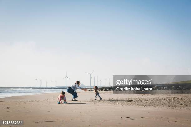 familj avslappnad på stranden nära vindkraftpark - asian on beach bildbanksfoton och bilder