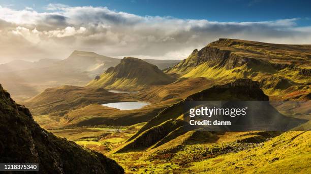 scenic view of quiraing mountains in isle of skye, scottish highlands, united kingdom. sunrise time with colourful an rayini clouds in background - scozia foto e immagini stock