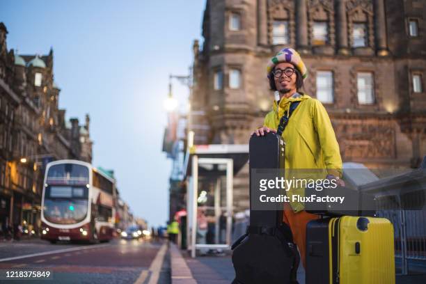 allegro musicista hipster in attesa di una corsa in taxi - custodia per chitarra foto e immagini stock