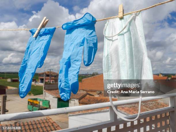 gloves and protective face masks hang out a clothesline rope against a sky with storm clouds - rope lava stock pictures, royalty-free photos & images