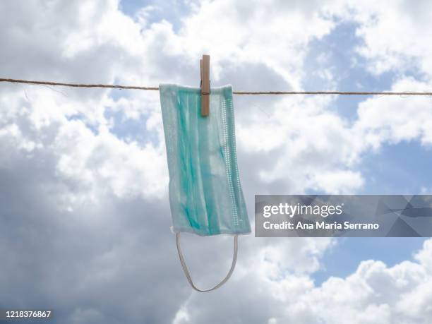 a protective face mask hang out a clothesline rope against a sky with storm clouds - rope lava stock pictures, royalty-free photos & images