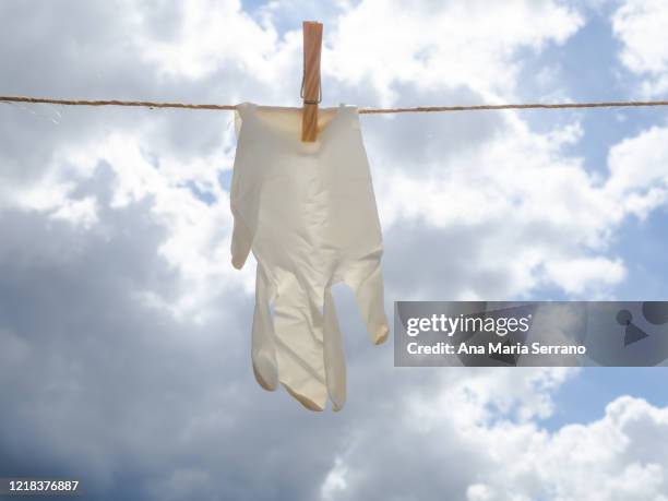 gloves hang out on a clothesline rope against a sky with storm clouds - rope lava stock pictures, royalty-free photos & images