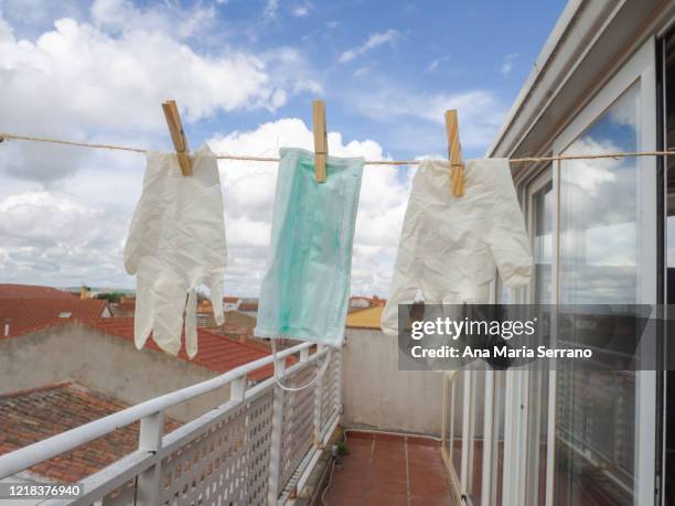 gloves and protective face masks hang out a clothesline rope against a sky with storm clouds - rope lava stock pictures, royalty-free photos & images