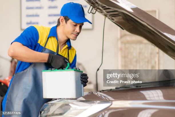 asian mechanic man changing car battery, engineer is replacing car battery because car battery is depleted. repair, car service and maintenance concept. - car battery stock pictures, royalty-free photos & images