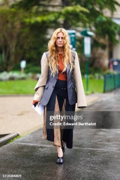 Blanca Miro wears a gray oversized jacket with beige flare sleeves, an orange wool pullover, a dark blue and brown skirt with printed patterns, black...