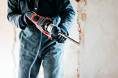 worker using pneumatic hammer drill to cut the wall concrete brick, close up