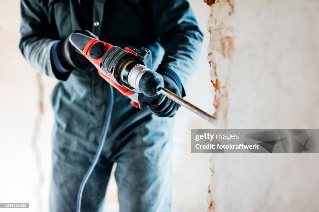 Worker using pneumatic hammer drill to cut the wall concrete brick, close up