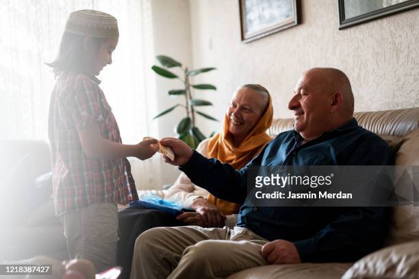 kid receiving money gift from grandparents in eid - arab old woman stock-fotos und bilder