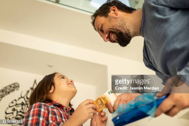 child getting eid money from father - two young arabic children only indoor portrait stock pictures, royalty-free photos & images