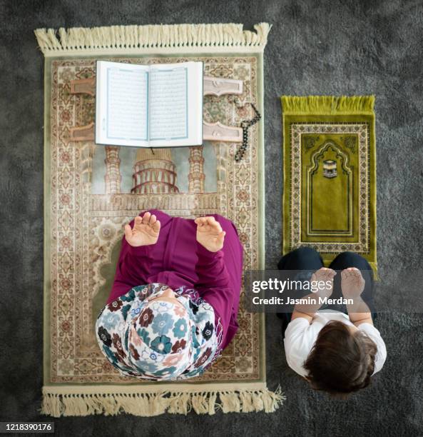 muslim family in living room praying and reading koran - american muslims celebrate eid al fitr with prayers imagens e fotografias de stock