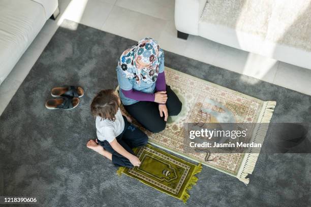 muslim family in living room praying and reading koran - american muslims celebrate eid al fitr with prayers imagens e fotografias de stock