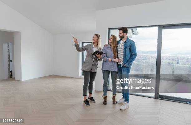 female real estate agent showing an apartment for sale to a young couple - move to new place stock pictures, royalty-free photos & images