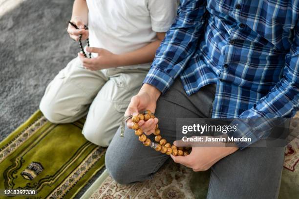 muslim family in living room praying and reading koran - american muslims celebrate eid al fitr with prayers imagens e fotografias de stock