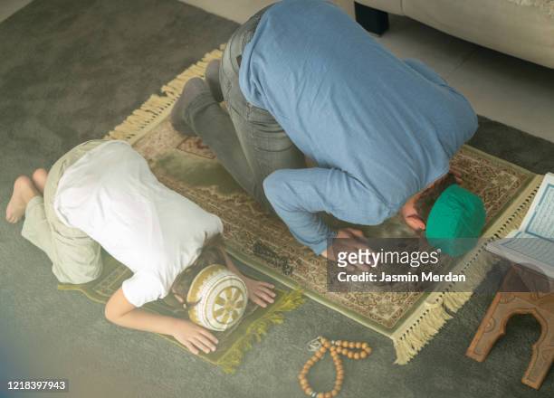 muslim family in living room praying and reading koran - american muslims celebrate eid al fitr with prayers imagens e fotografias de stock