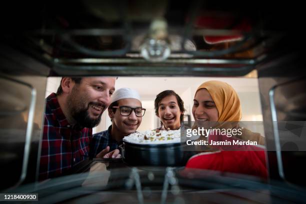 family baking sweet in oven - iftar photos et images de collection