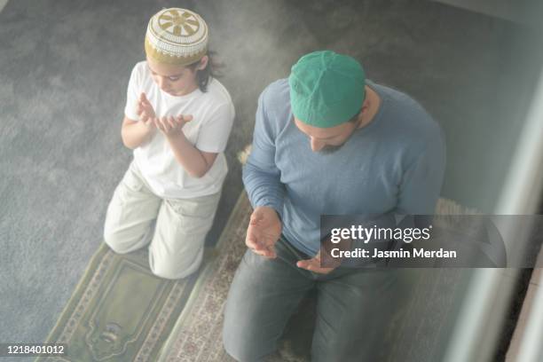 muslim family in living room praying and reading koran - american muslims celebrate eid al fitr with prayers imagens e fotografias de stock