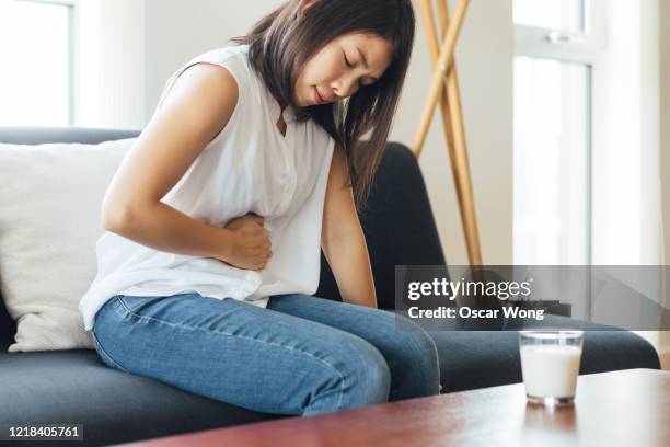 young woman suffering stomach at home - indigestión fotografías e imágenes de stock