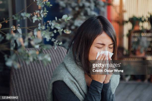 sick young woman blowing nose - sonarse fotografías e imágenes de stock
