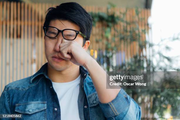 young man rubbing eye with hand - red eye stock-fotos und bilder