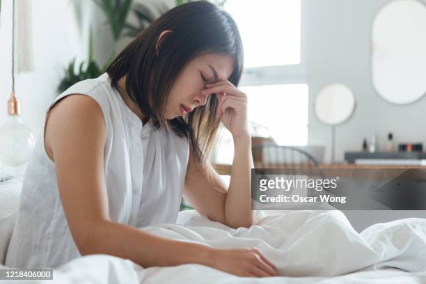 young woman suffering headache in bed - exhaustion stock-fotos und bilder