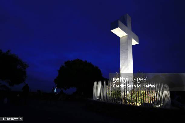 Large cross is lit up prior to a sunrise Easter service at Mt. Helix Park as crews prepare cameras to stream the service on April 12, 2020 in San...