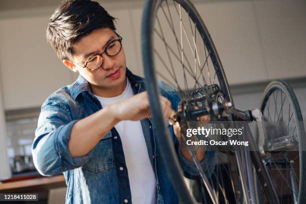 focused young man repairing bicycle at home - adjusting ストックフォトと画像